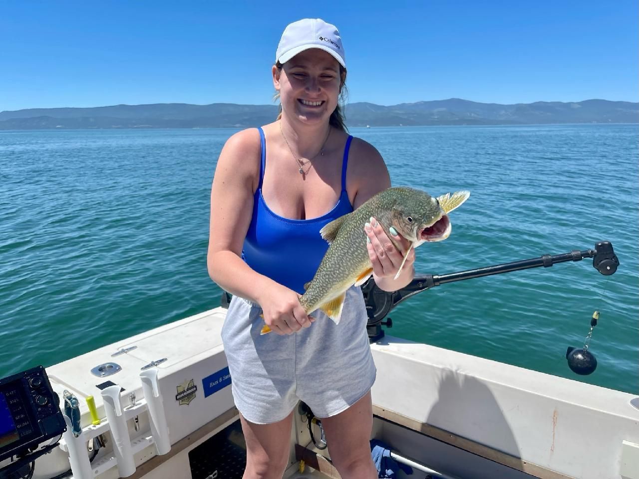 A woman is holding a fish on a boat in the water.