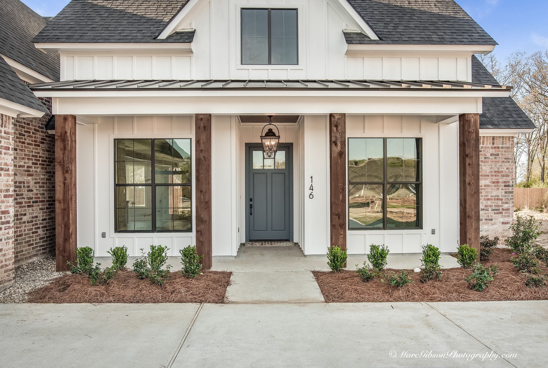 Farmhouse style home with a gray door and brick accents.