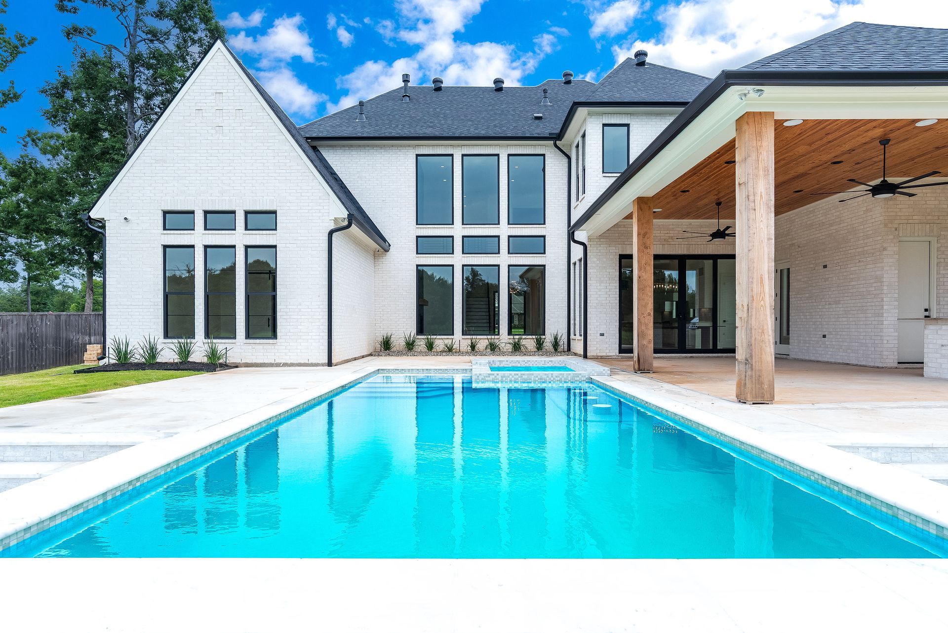 Modern white house with a pool; blue water reflects the sky.