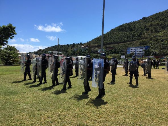 Public order training in the Caribbean outside in formation using shields that provide protection from chin to to knee