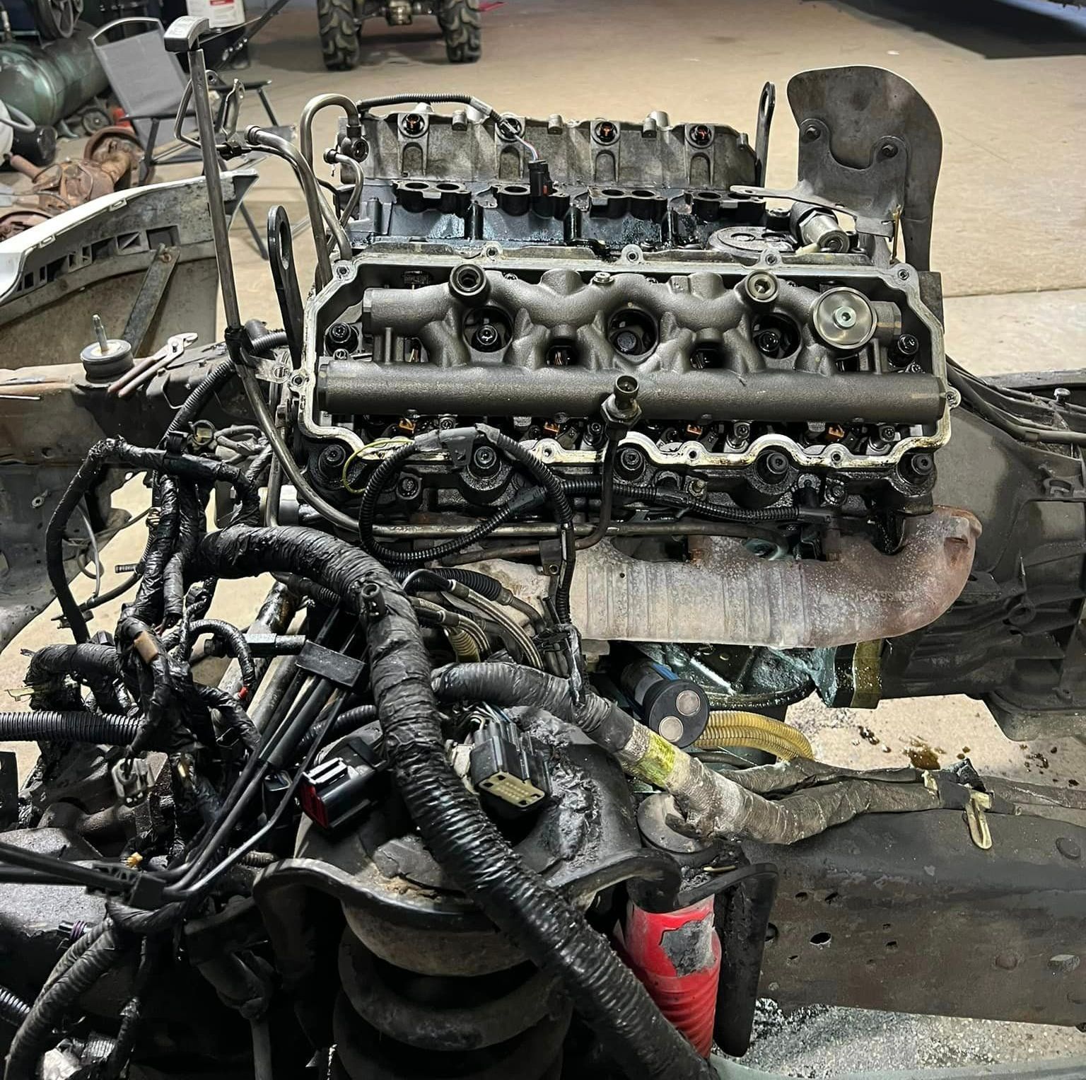 Engine removed from vehicle; tangled wires, components visible, likely for repair.