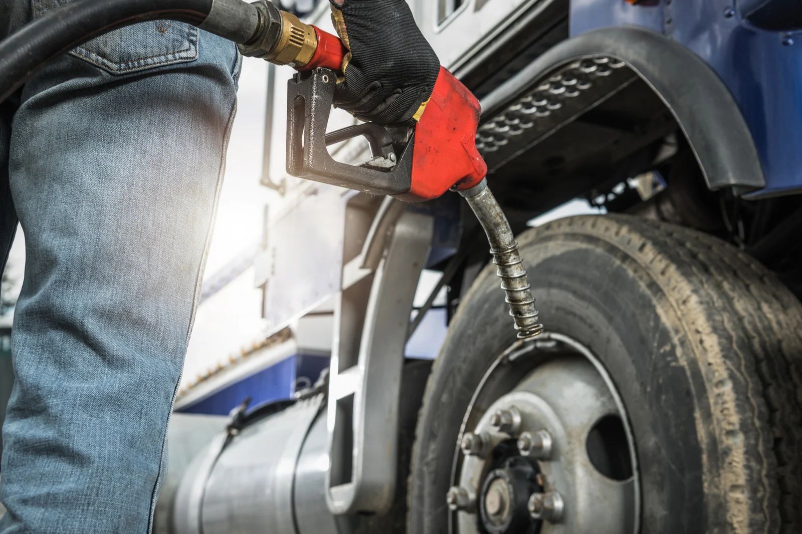 Person refueling a truck tire with a hose at a gas station