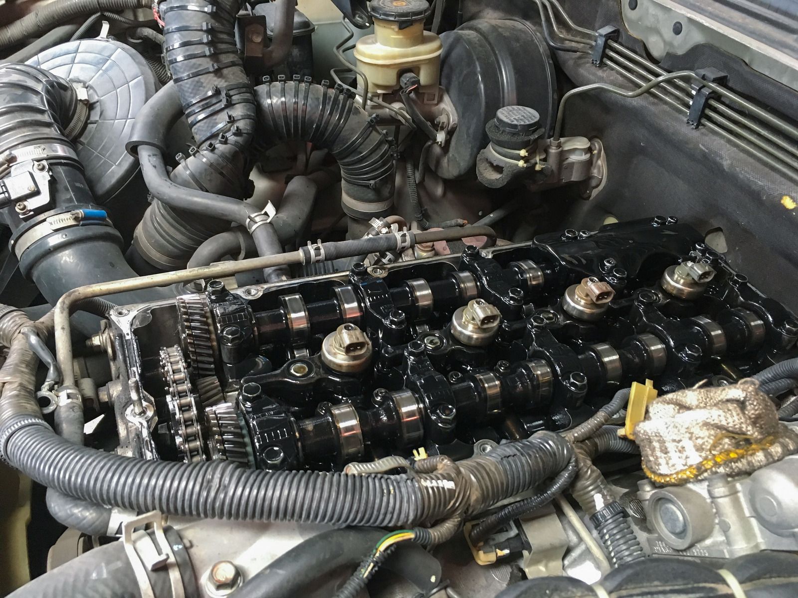 Car engine with the valve cover removed, exposing camshaft and rocker components in the engine bay