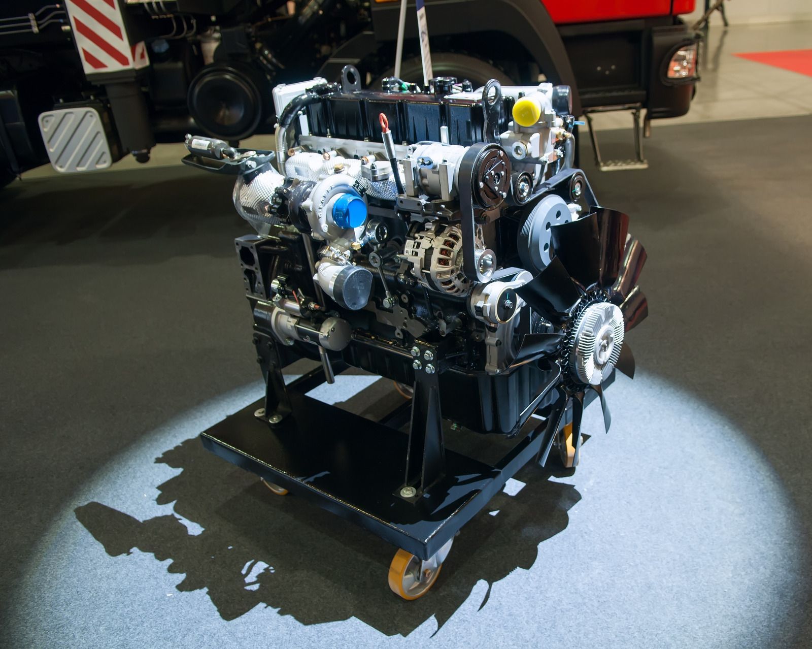 Engine on a stand in a workshop, spotlighted with black frame and exposed silver components.