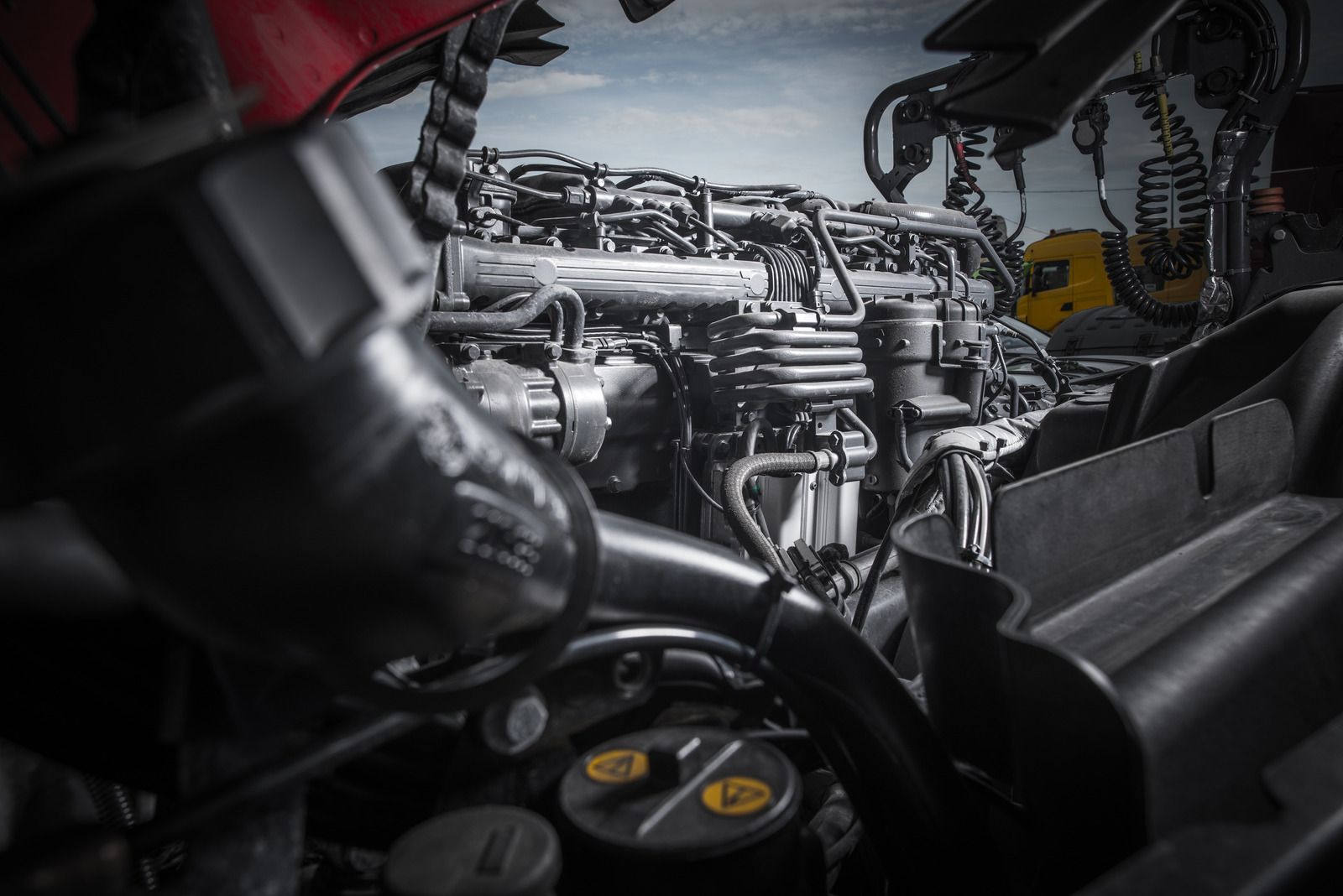 Close-up of a vehicle engine bay with visible hoses, wiring, and metallic components