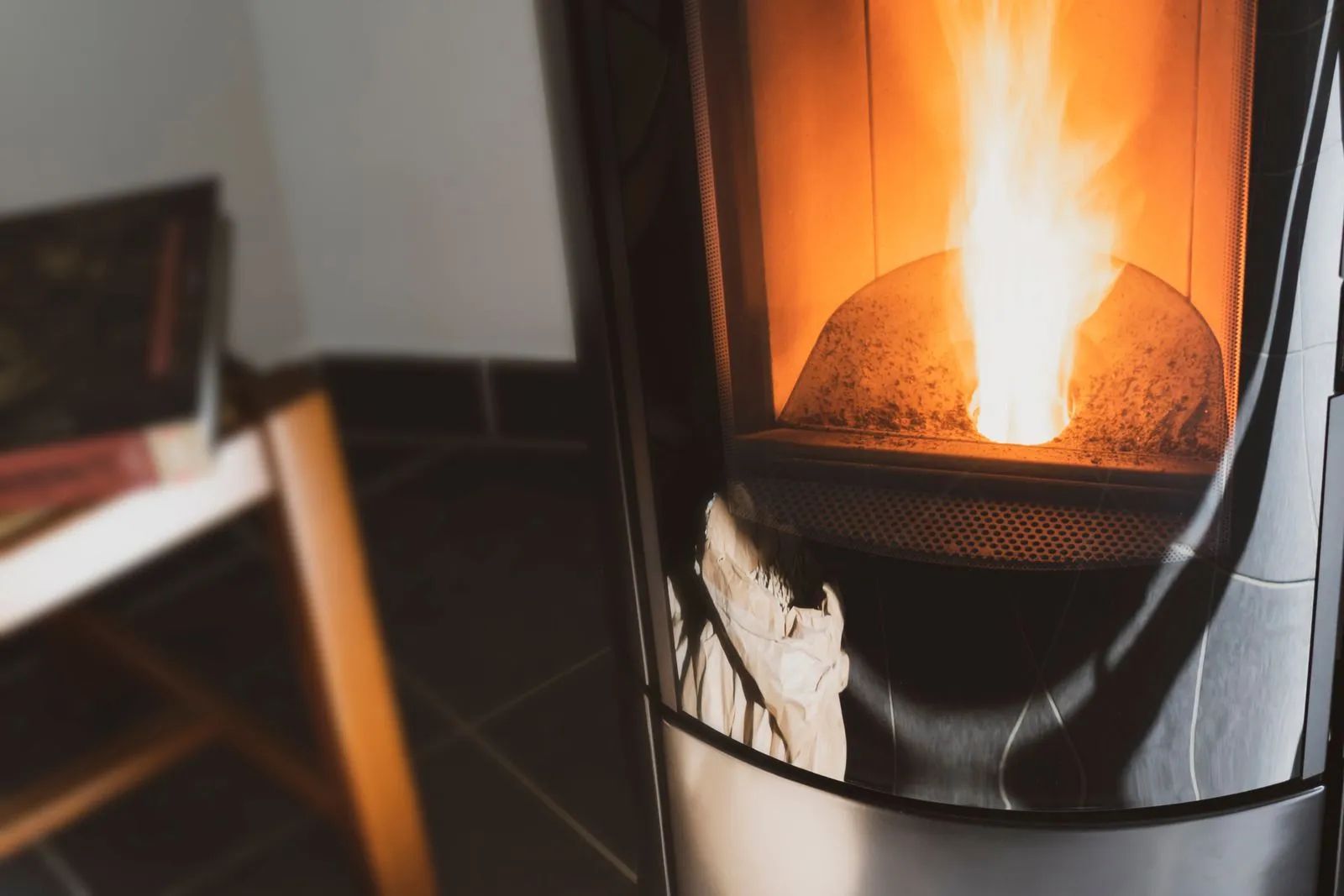 A pellet stove with bright flames burning beside a couch in a dim living room.