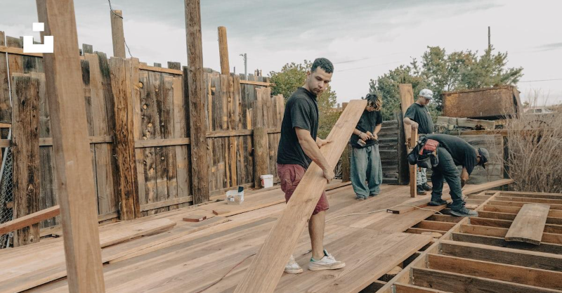 Crew carries long lumber across a deck frame during Deck Building Services in Grand Junction, CO for a new backyard deck