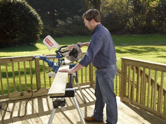 Carpenter cuts deck boards with a miter saw during Deck Building Services in Grand Junction, CO for precise deck framing
