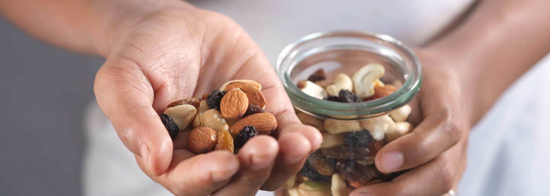 Picture of someone holding various types of nuts in a jar. 