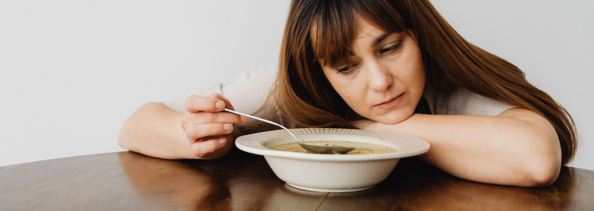 Picture of a woman looking a bowl of soup. 