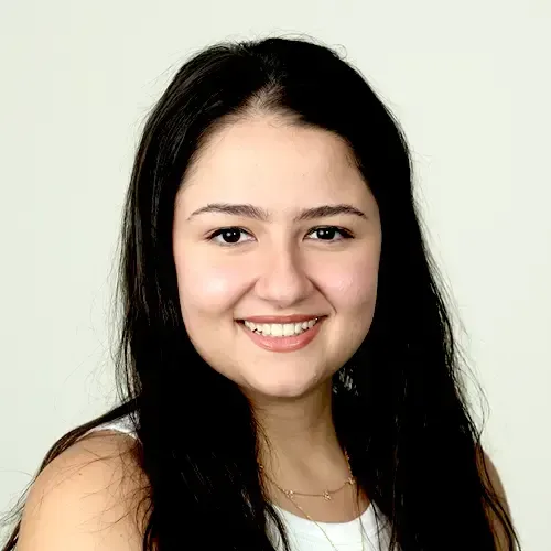A woman in a black tank top is smiling in front of a green door.