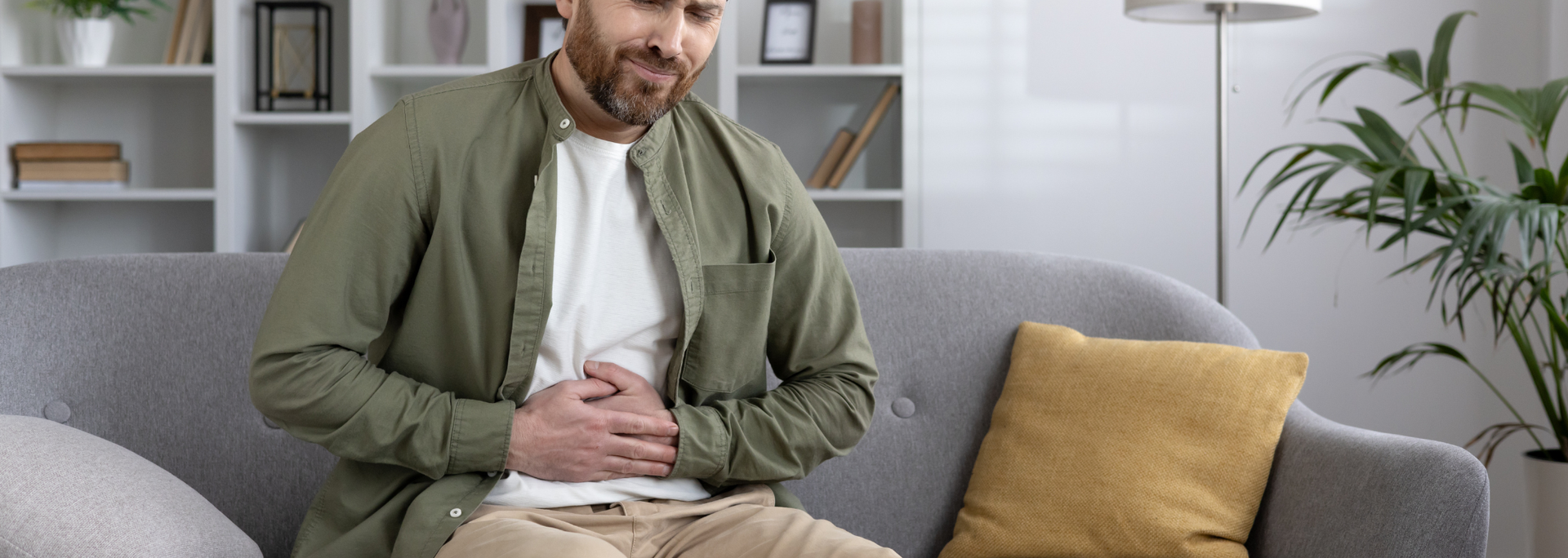 Picture of a man clutching their stomach in mild discomfort. 