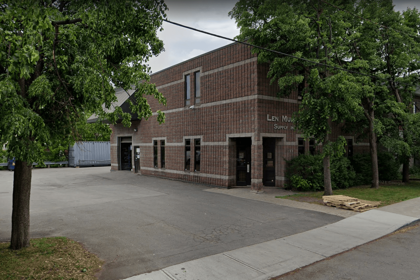Un grand bâtiment en briques avec un parking devant.