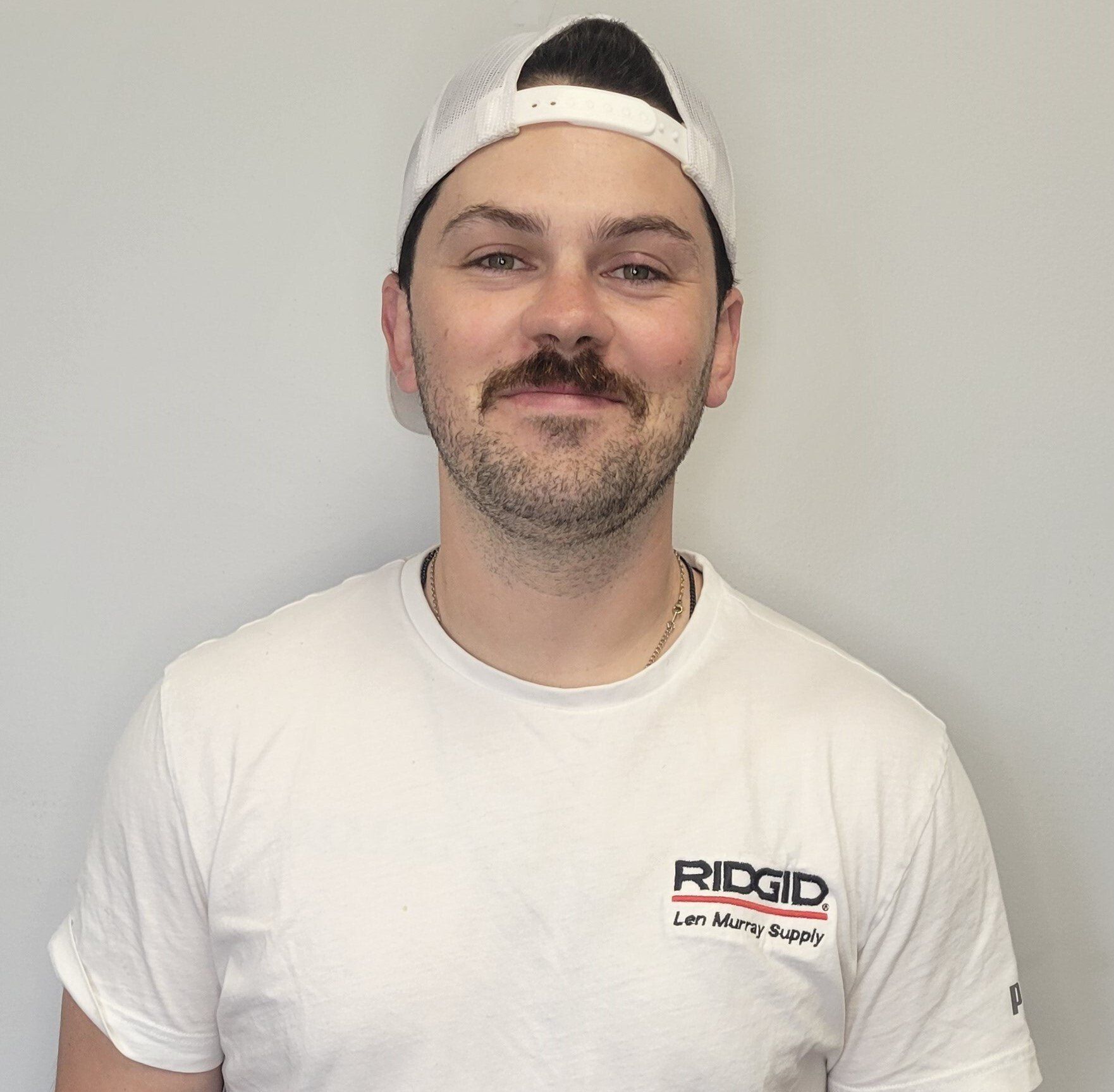 Un homme portant un chapeau blanc et un t-shirt blanc avec le mot ridgid dessus.