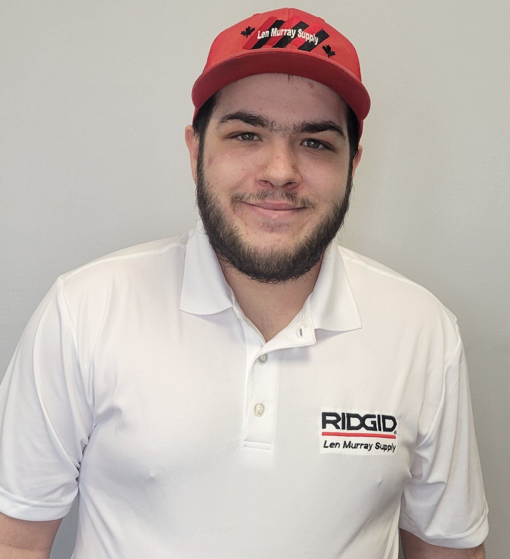 Un homme portant un chapeau rouge et une chemise blanche avec le mot ridgid dessus.