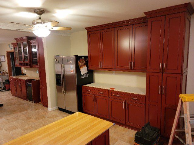a kitchen with red cabinets and a stainless steel refrigerator