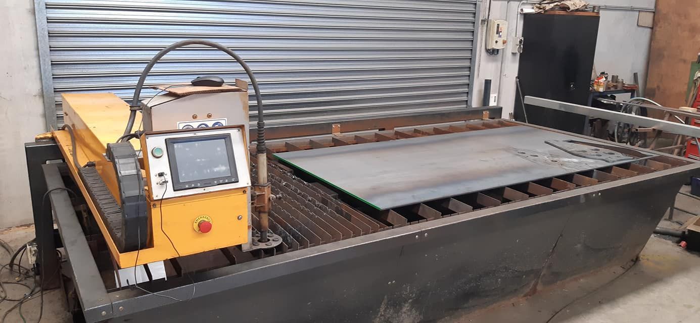 Industrial machine with yellow control box beside a metal platform in a workshop