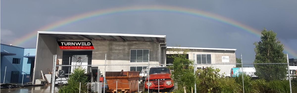 Building with a rainbow in the sky and parked cars in front