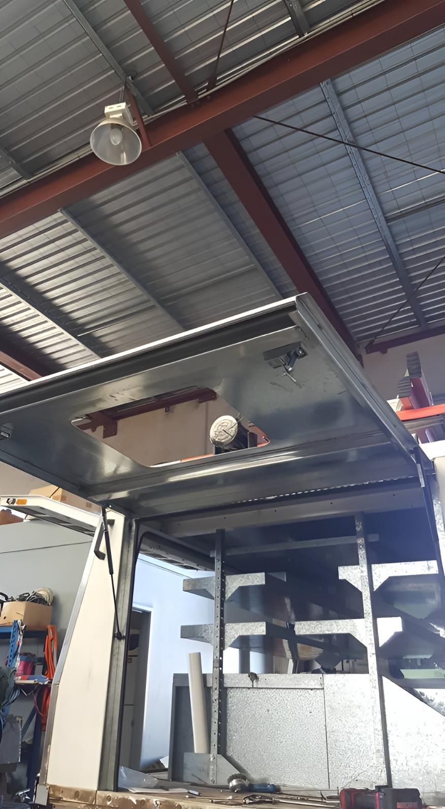 Open ceiling in a workshop reveals attic storage and a person working below in a garage-like space