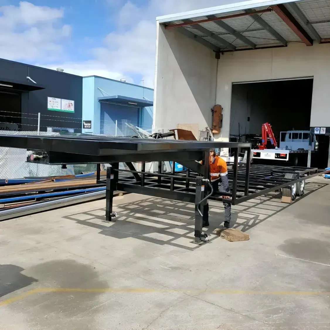Industrial loading dock with a truck trailer ramp and a worker in orange vest near a warehouse opening