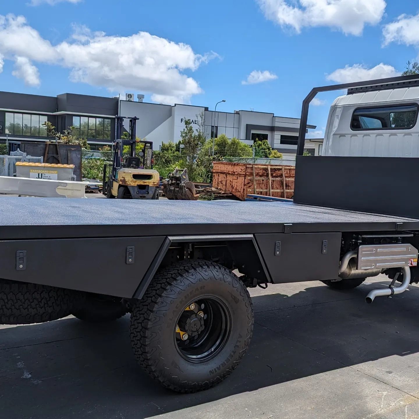Flatbed truck parked outdoors at a construction site under a blue sky
