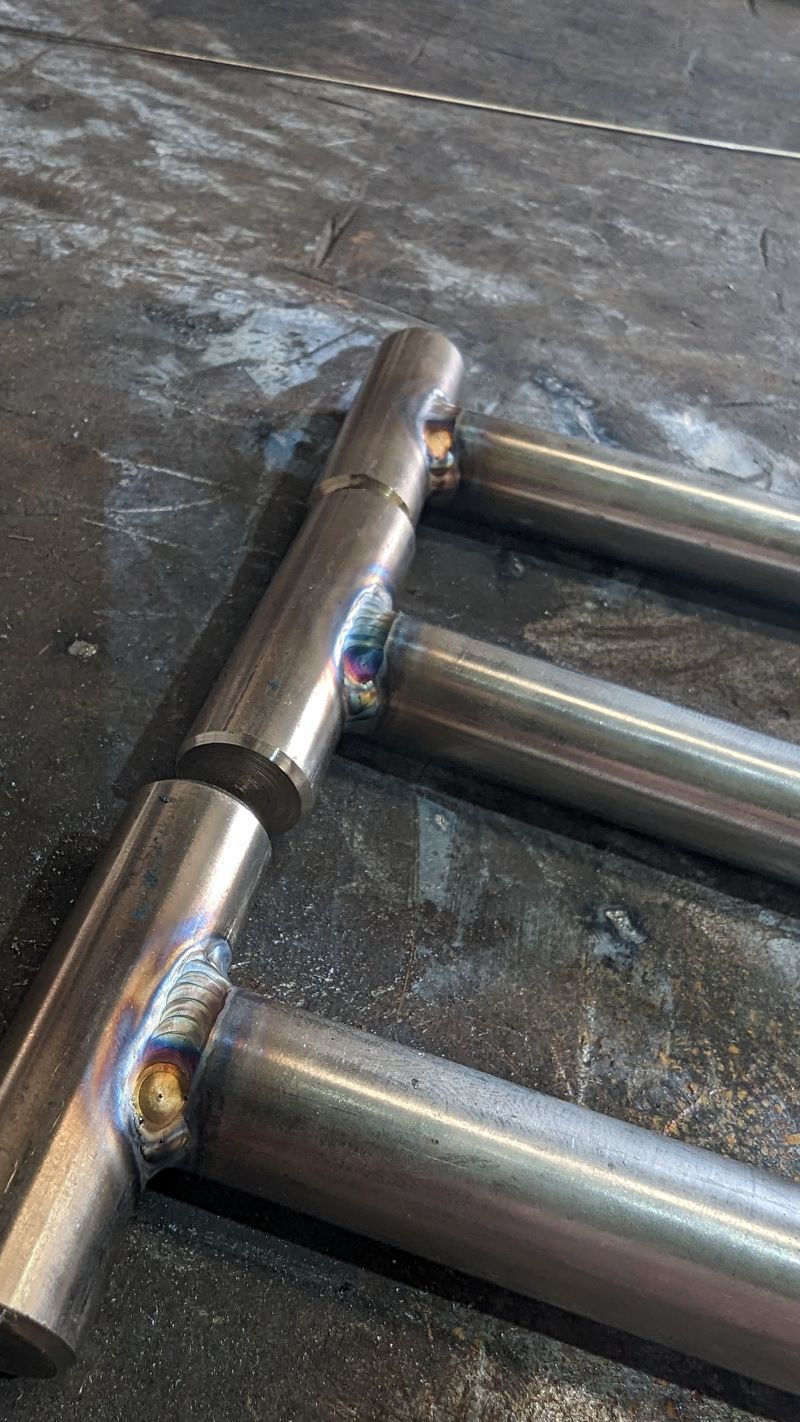 Close-up of welded metal rods forming a ladder-like frame on a dark work surface