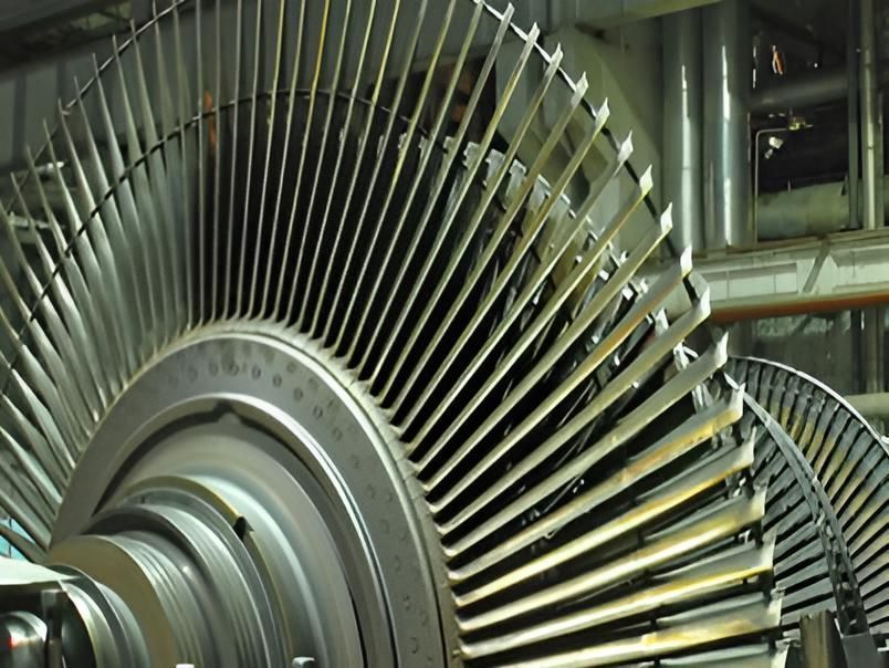 Close-up of a large industrial turbine with metal blades and shaft inside a factory setting
