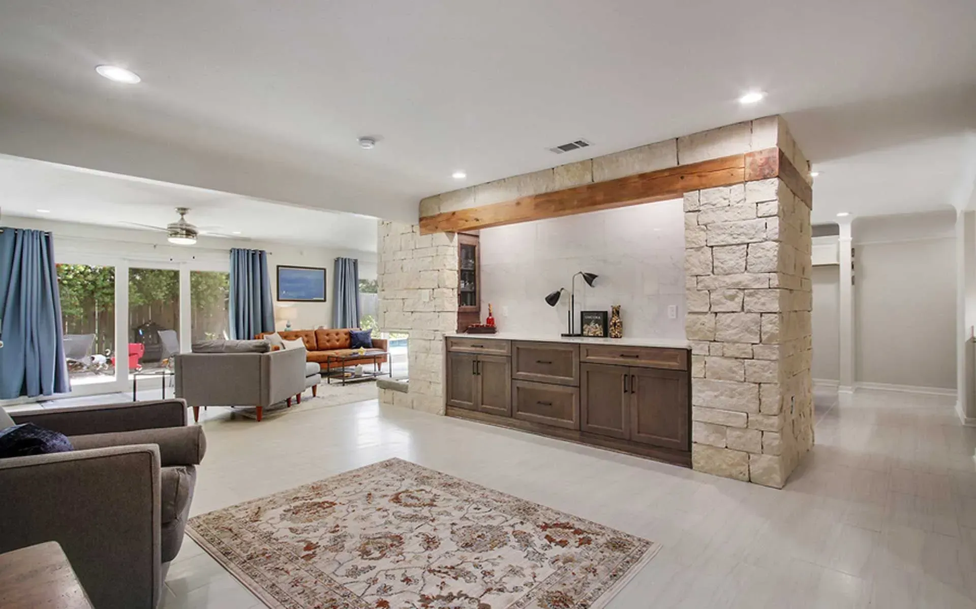 Living room with stone wall feature, wood cabinetry, area rug, and seating.