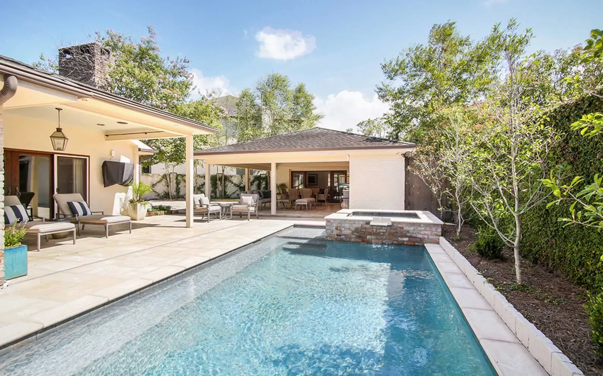 Pool and patio area with a long pool, spa, and outdoor seating under a covered patio.