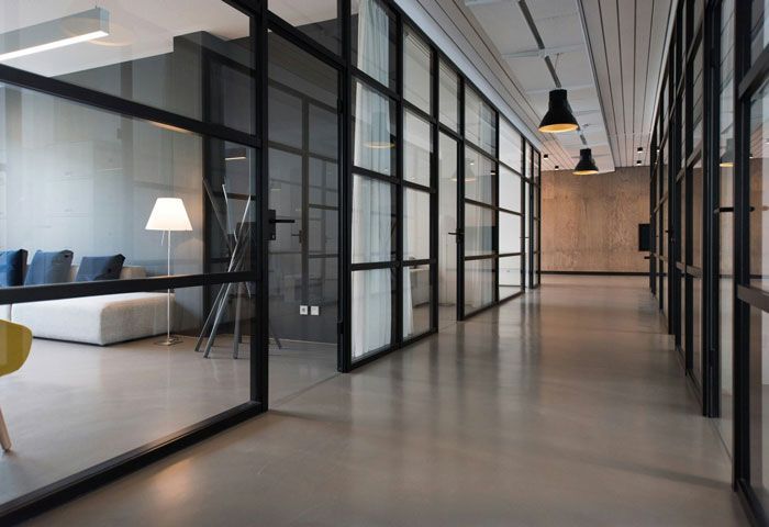 A long hallway with a lot of glass walls and a lamp hanging from the ceiling.