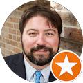 A man with a beard is wearing a suit and tie.