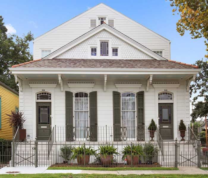 A white house with green shutters and a fence