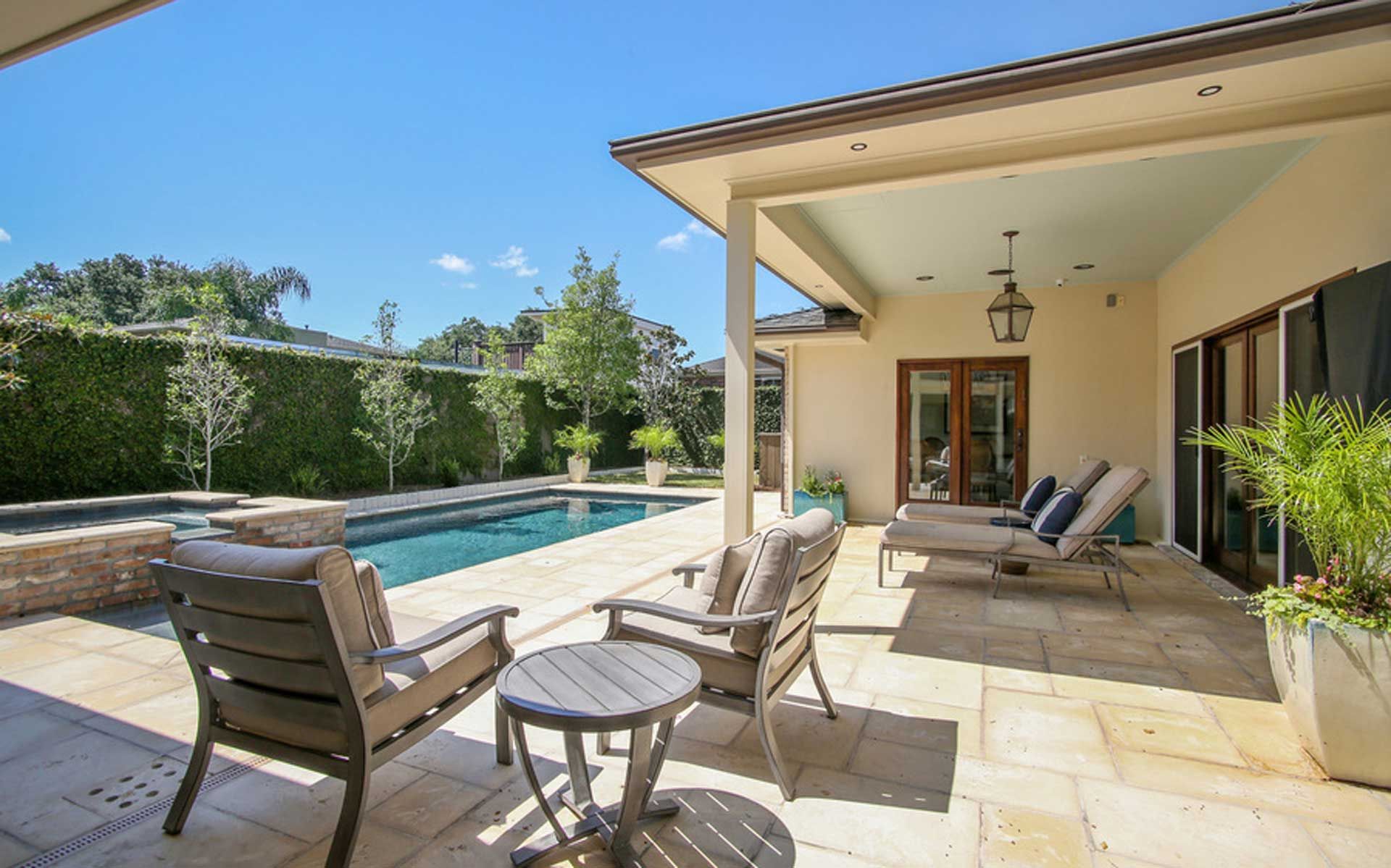 A patio with chairs and a table next to a swimming pool