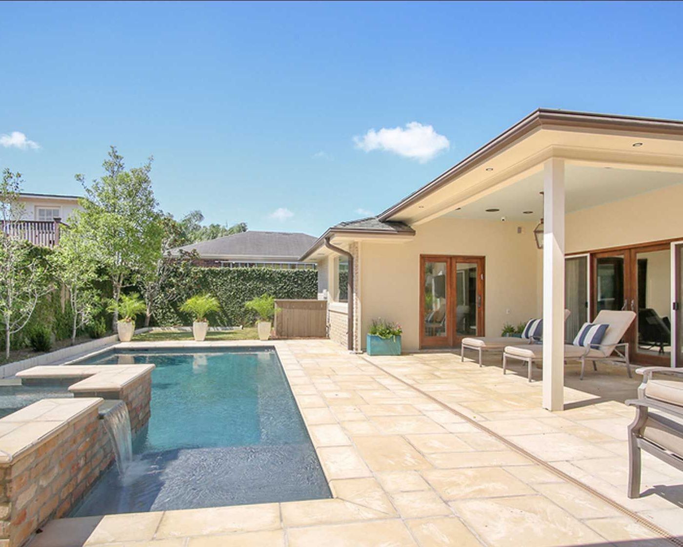 A large swimming pool is in the backyard of a house