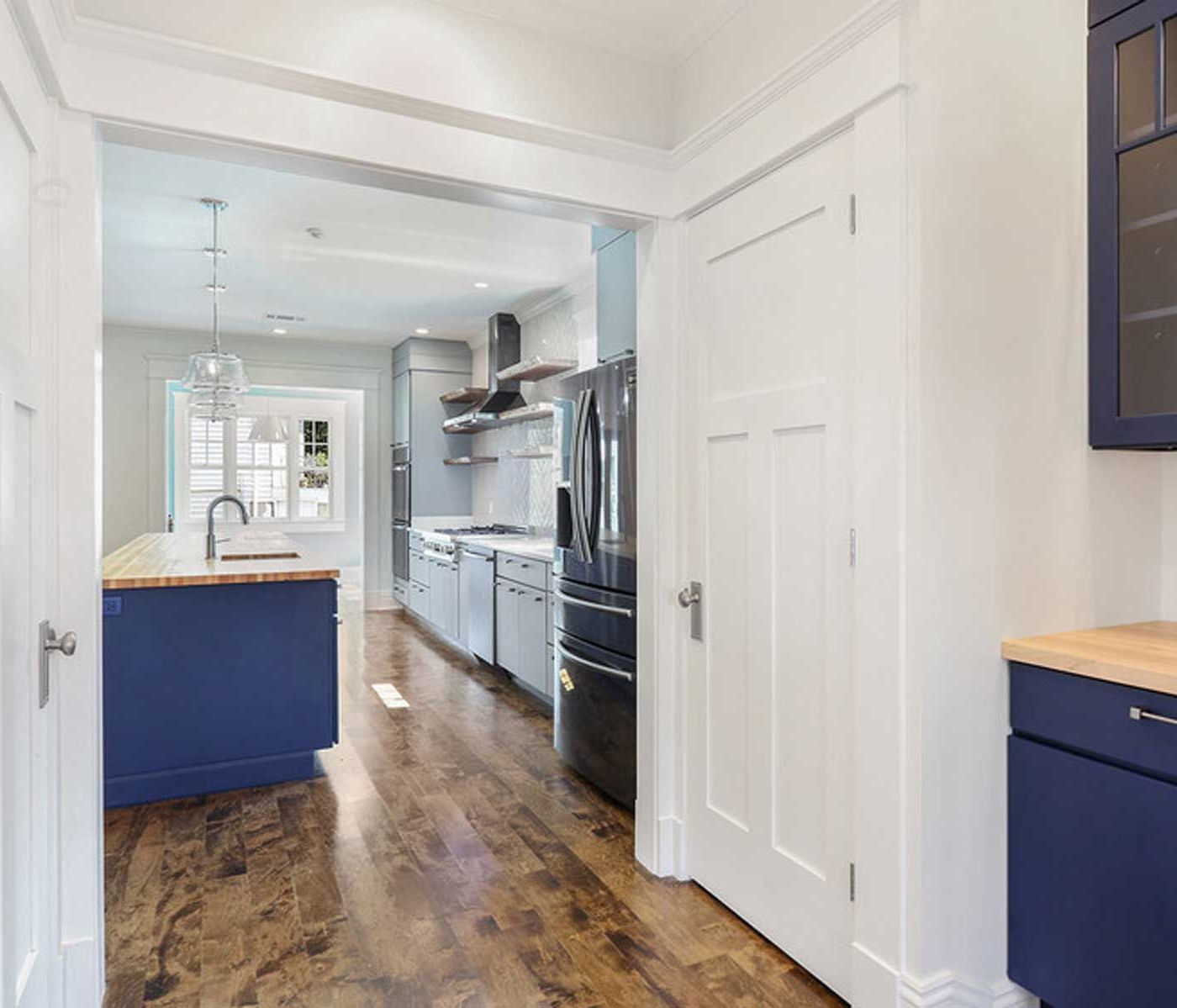 A kitchen with blue cabinets and a black refrigerator