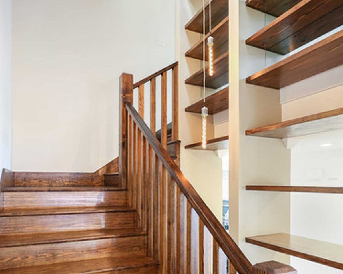 A wooden staircase with a wooden railing and shelves