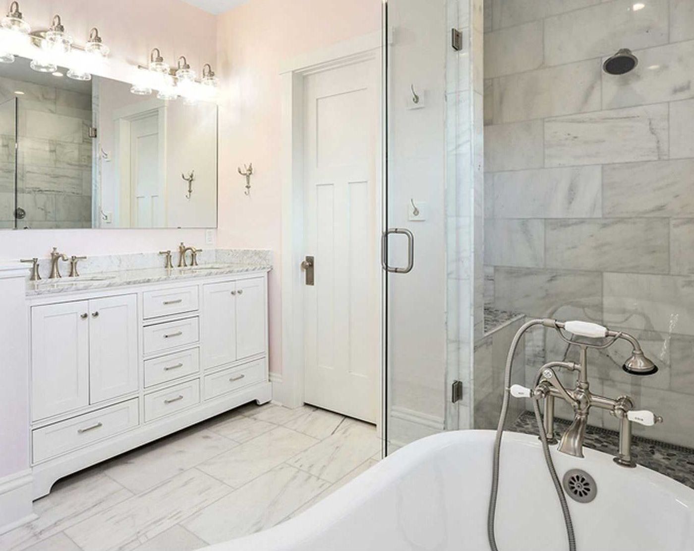 A bathroom with two sinks , a tub , a shower and a mirror.