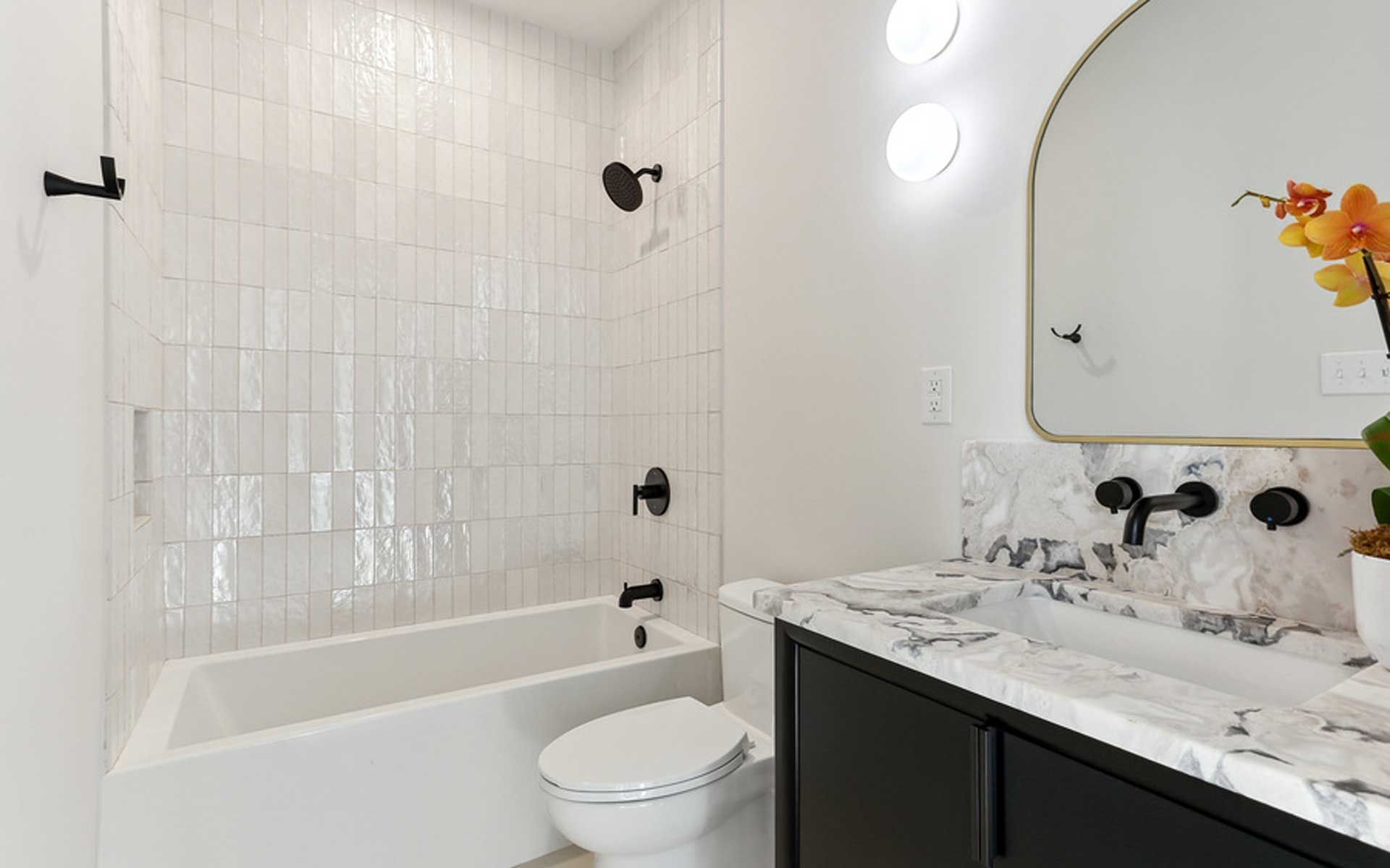 A bathroom with a toilet , tub , sink and mirror.