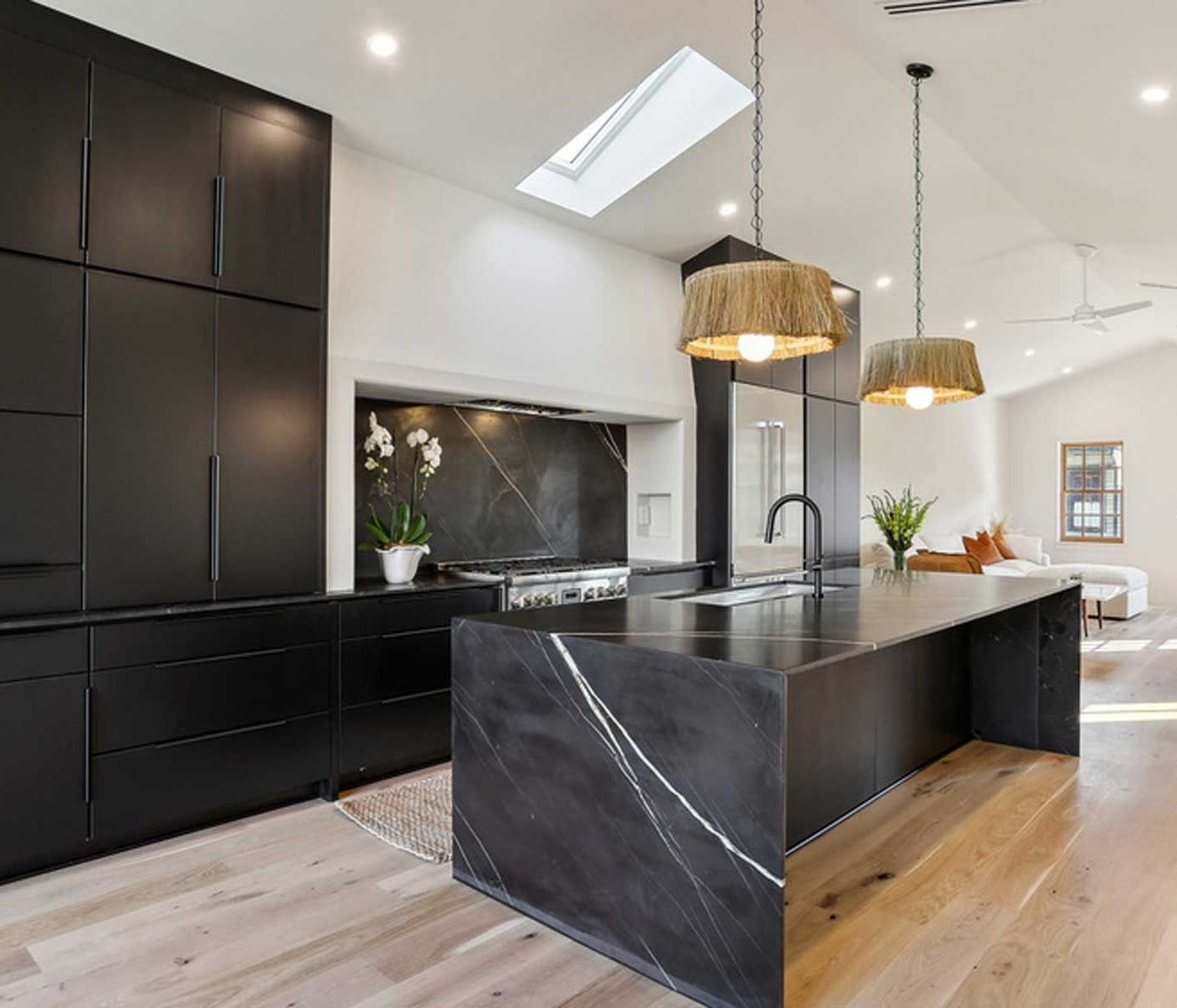 A kitchen with black cabinets and a large island in the middle.