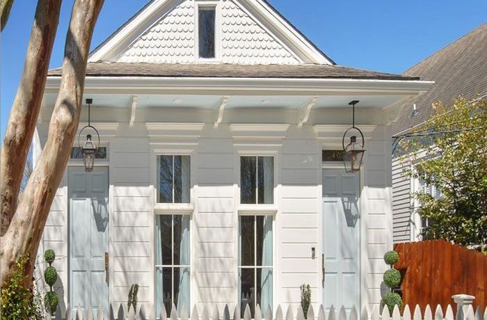 A white house with blue shutters and a white picket fence