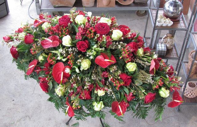 Una sontuosa composizione floreale per la bara, con rose rosse