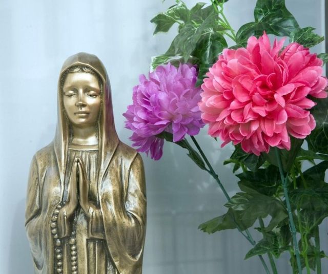 Una statua color bronzo raffigurante una persona in preghiera con gli occhi chiusi