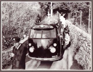 Un furgone Volkswagen nero d'epoca, decorato con fiori e palloncini come un carro funebre