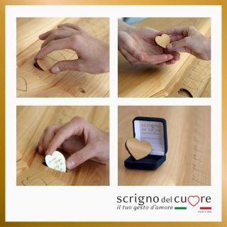 Un montaggio in quattro parti che mostra delle mani che depongono dei piccoli cuori di legno in una bara di legno