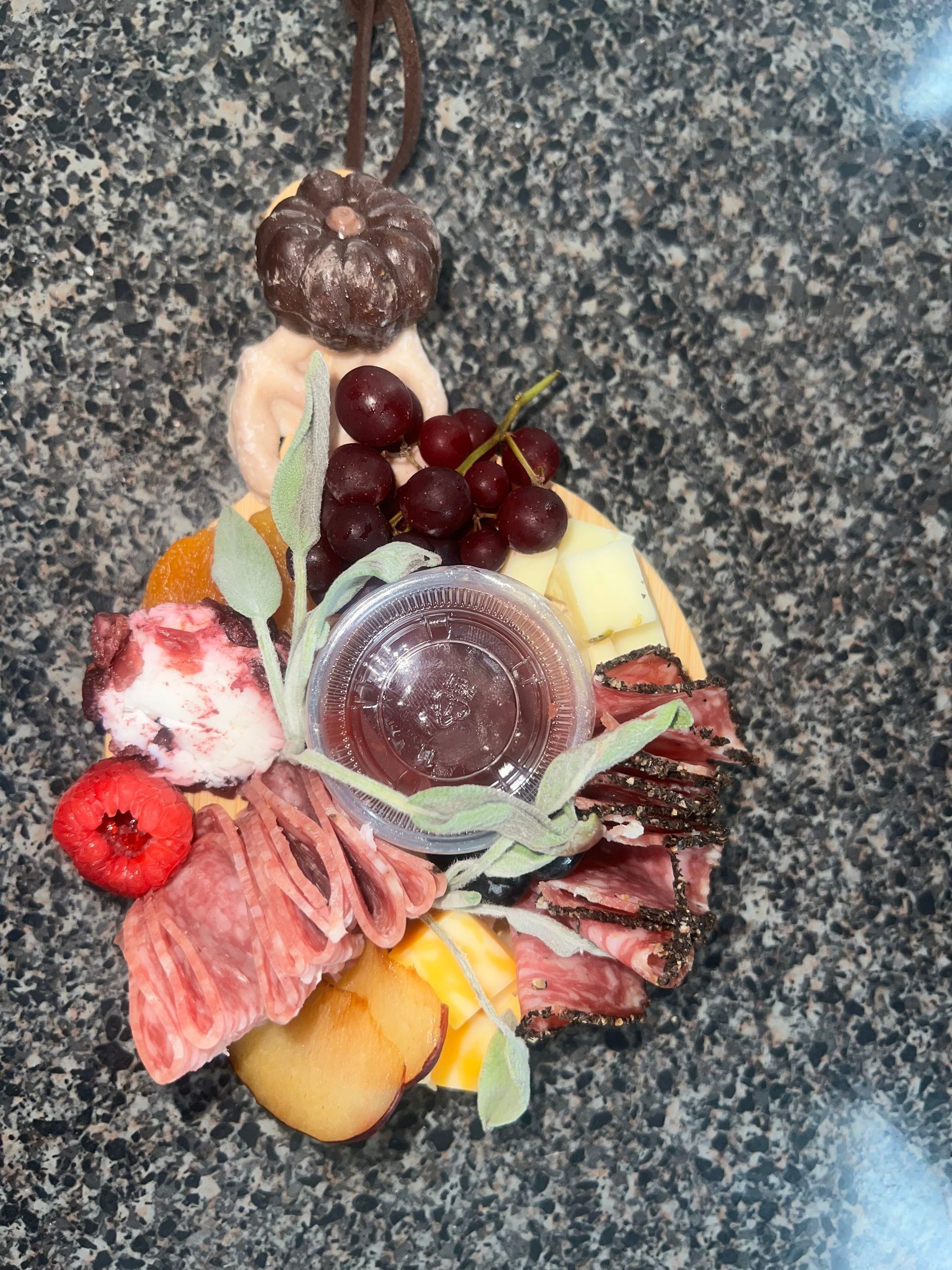 Charcuterie board with grapes, cheeses, salami, strawberries, crackers, and dip on a granite countertop
