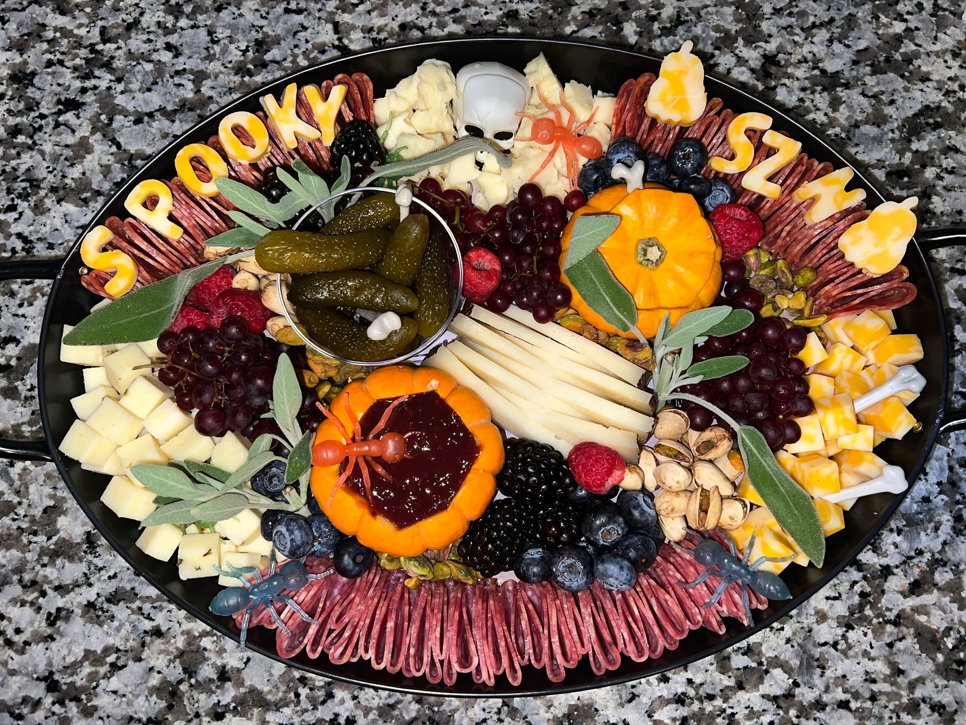 Charcuterie board spelling “PROUDLY SINGLE” with meats, cheeses, fruit, and crackers