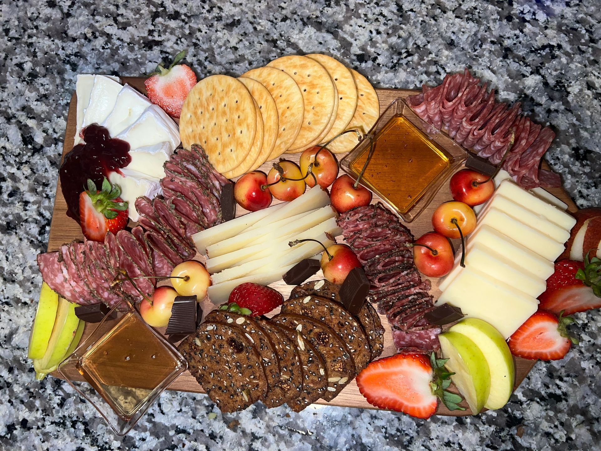 Assorted cheeses, crackers, meats, fruits, and nuts arranged on a charcuterie board