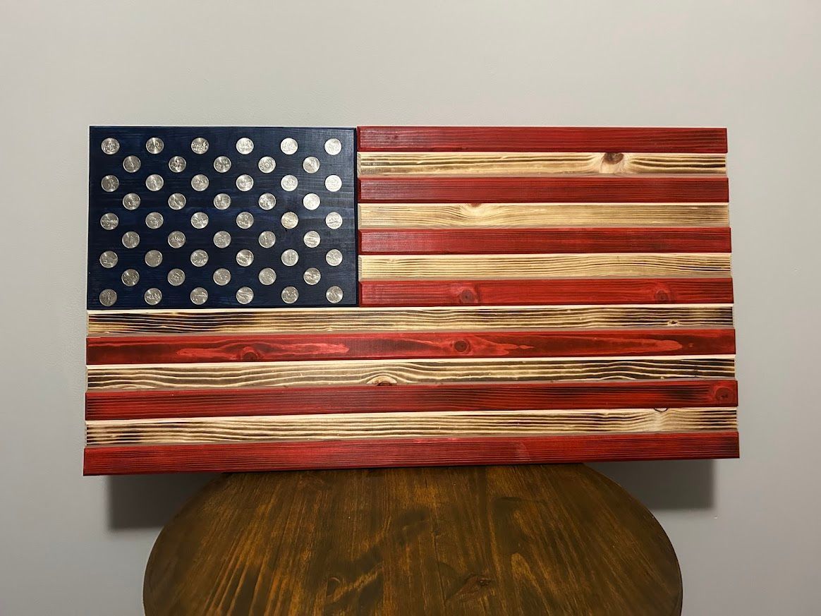 Wooden American flag with painted blue canton and silver star-like accents, red and tan stripes.