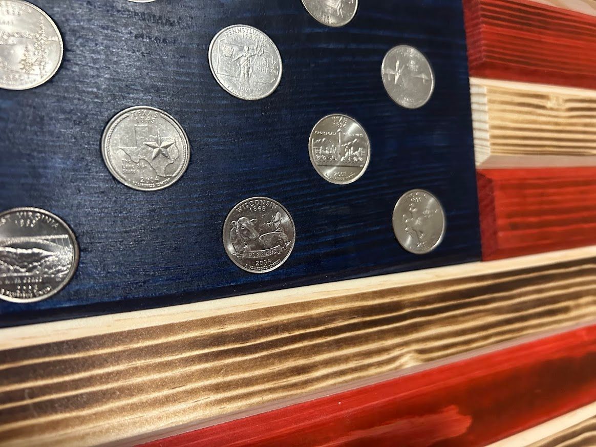 Wooden American flag with painted blue canton and silver star-like accents, red and tan stripes.