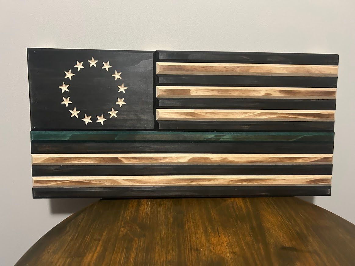 Wooden thin green line flag with 13 stars in a circle.